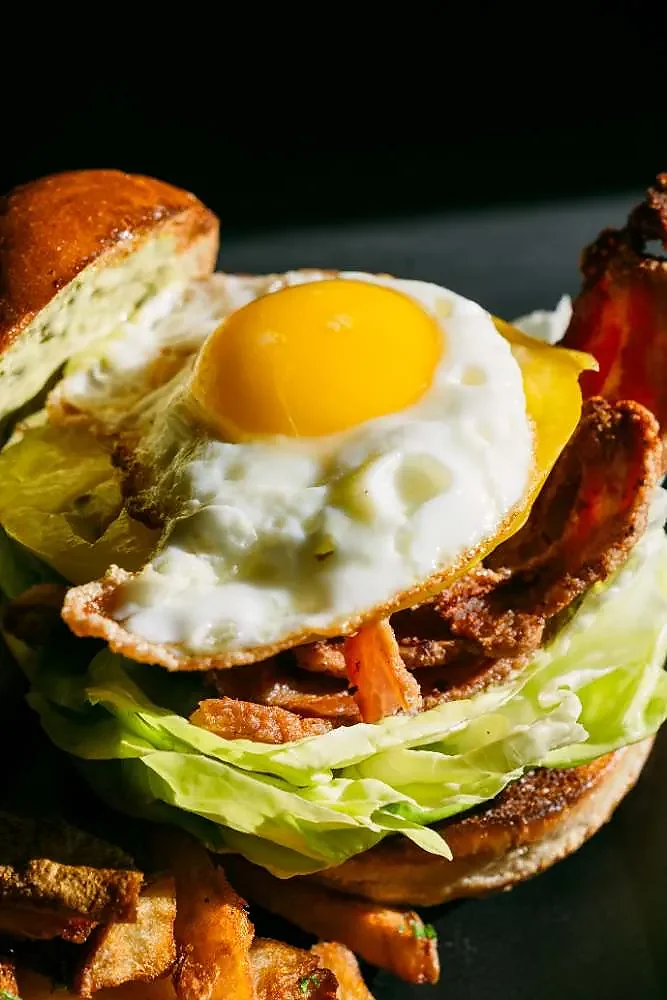 Fried egg and bacon sandwich on brioche with fries