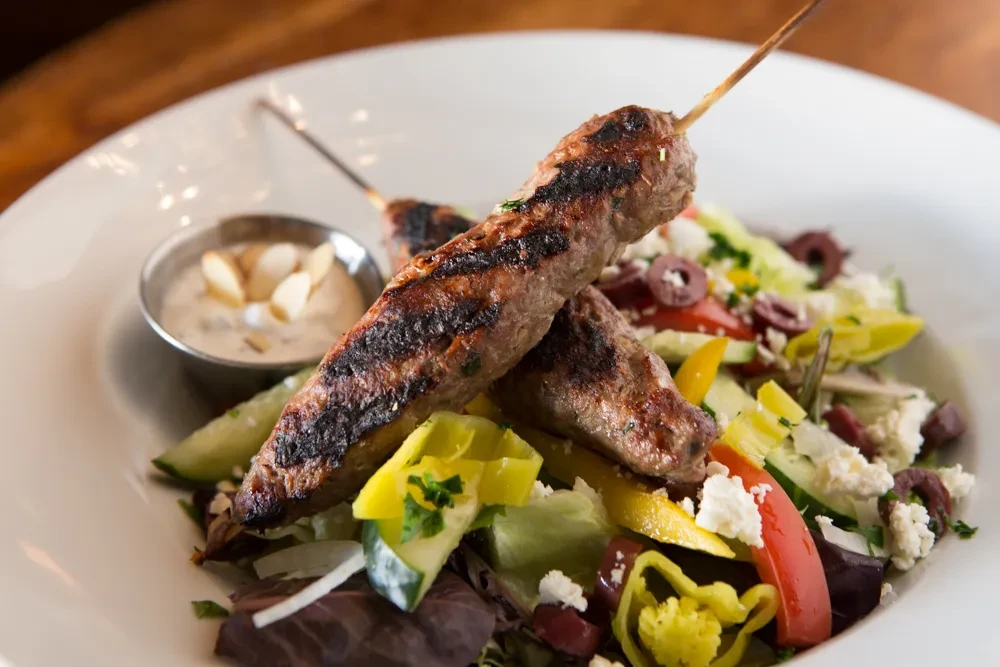 Grilled meat skewers, mixed salad with feta, and almond dipping sauce.