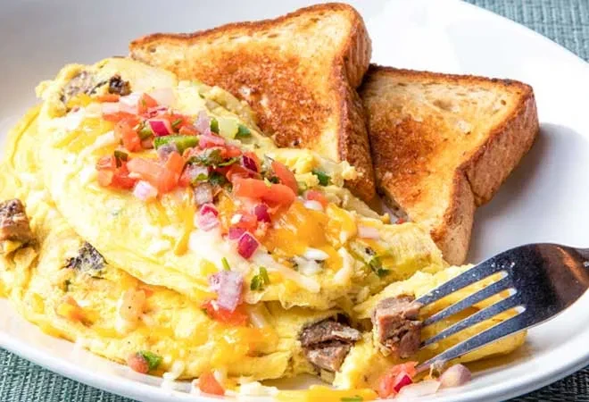 Fluffy eggs with pico de gallo, melted cheese, meat, and toast.