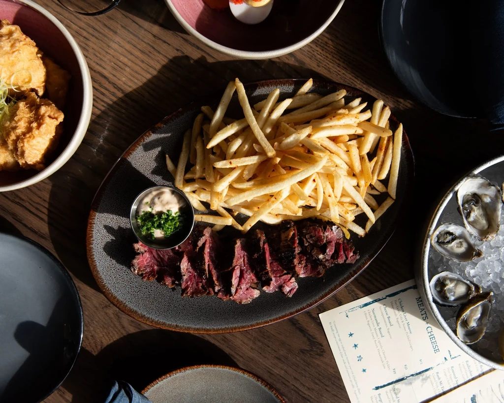 Restaurant table with steak, fries, fried chicken, and oysters on ice.
