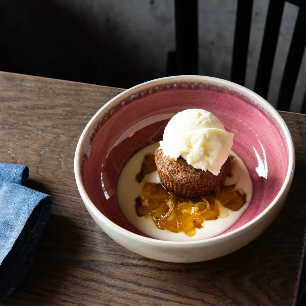 Warm cake, vanilla ice cream, custard, and candied fruit in a bowl.