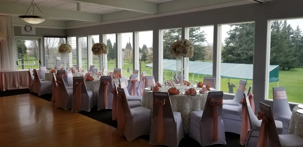 Formal dining hall with white and rose-gold decor overlooking golf course.