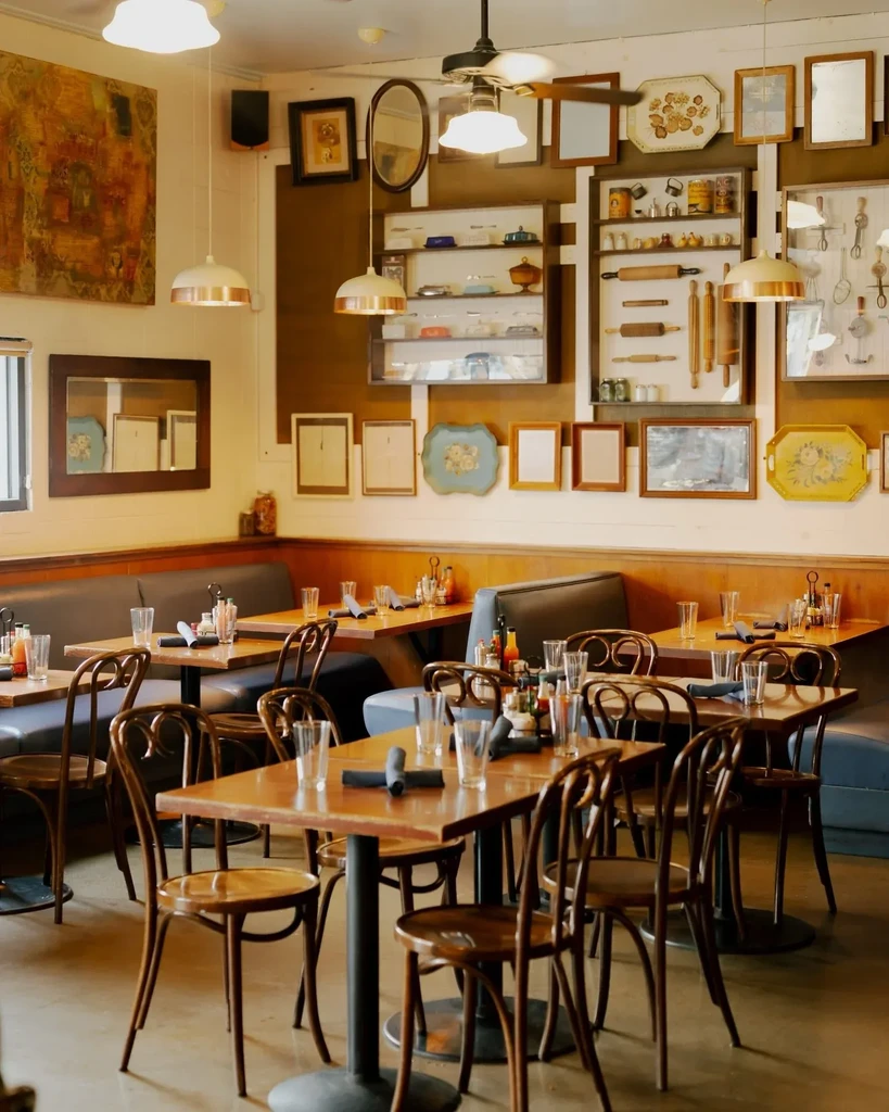 Well-lit, empty restaurant dining area with wooden tables, booths, and eclectic decor.