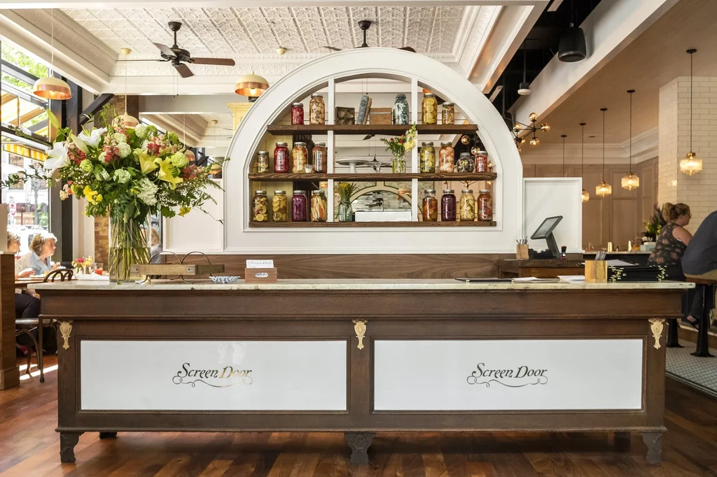 Ornate 'Screen Door' counter with marble top, backed by jarred goods.