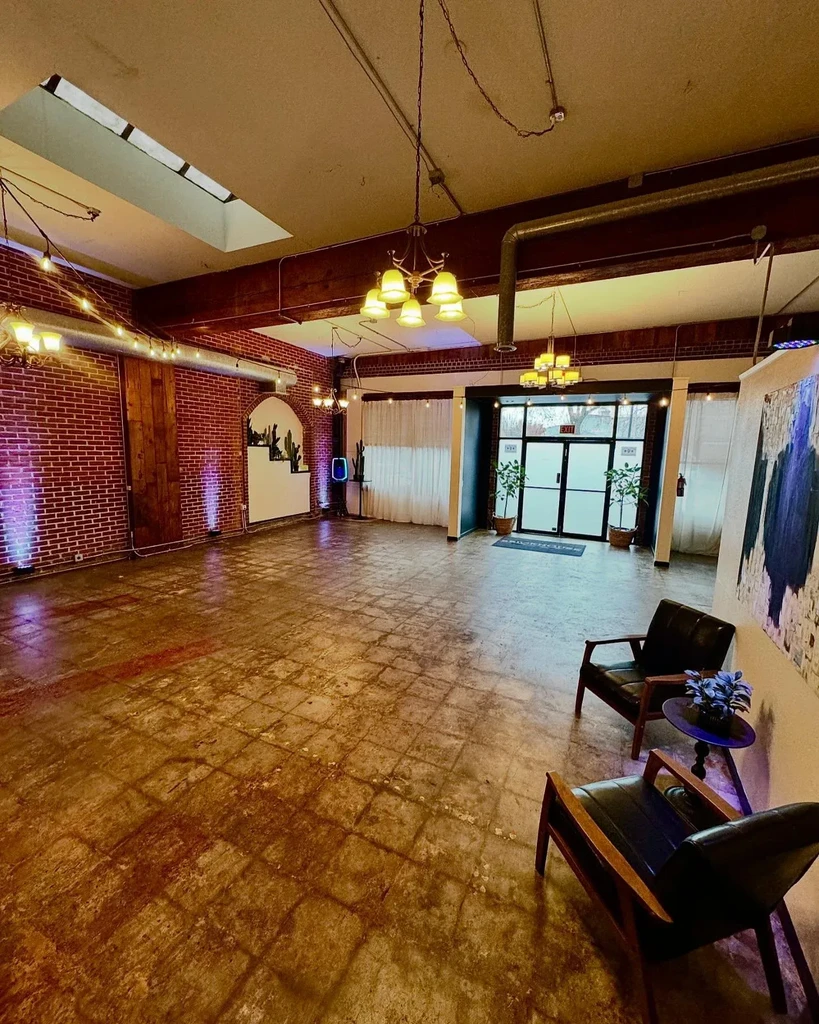 Empty industrial modern event space with exposed brick and high ceiling.