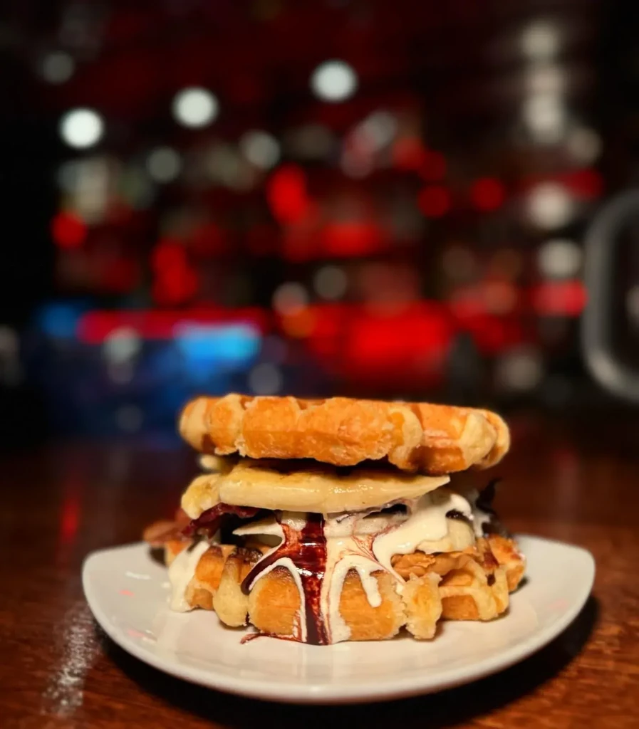 Golden waffle sandwich with banana, bacon, cream, chocolate sauce, dripping.