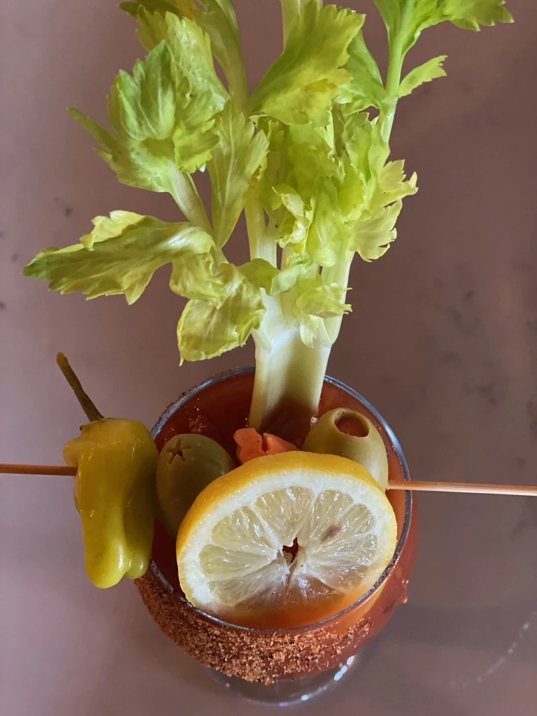 Heavily garnished Bloody Mary with celery, olives, lemon, and a spice rim.