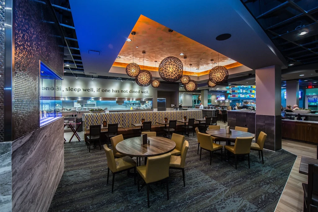 Upscale modern restaurant interior with geometric lighting, open kitchen, and bar.