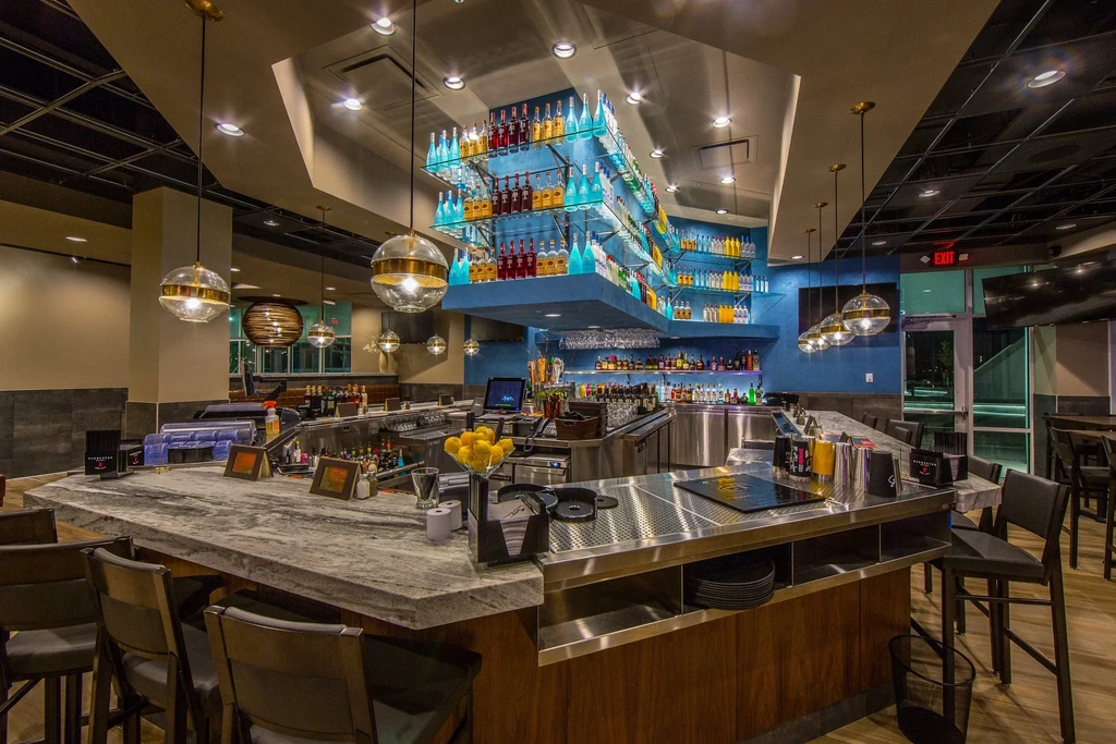 Empty, modern bar with illuminated bottles on a stylish back bar.