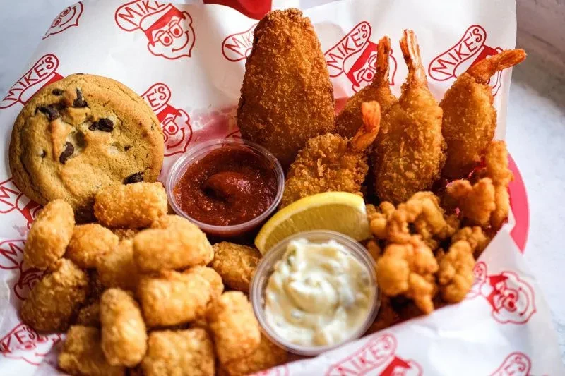 Mike's fried seafood platter with tots, cookie, sauces, and lemon.
