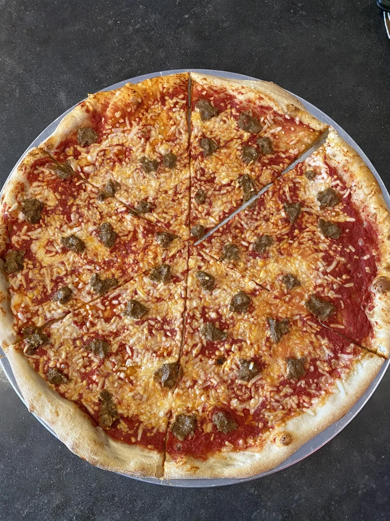 Whole, sliced sausage and cheese pizza on a silver pan.