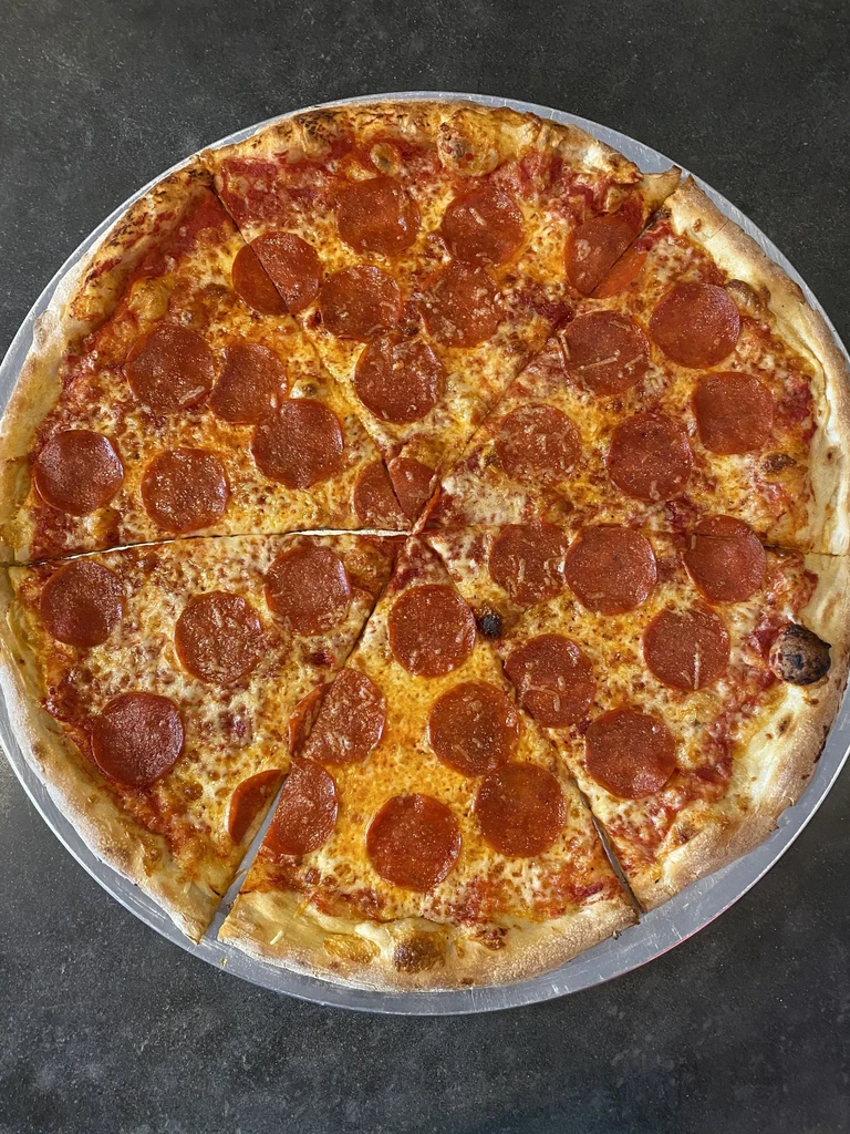 Large pepperoni pizza, cut into eight slices, on a metal pan.