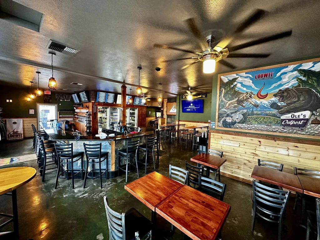Empty restaurant interior with bar, tables, and colorful brewery mural.