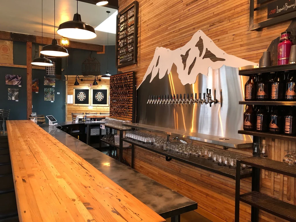 Rustic Loowit brewpub interior with bar, taps, bottles, and dartboards.