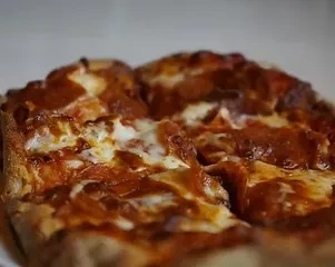 Rectangular deep-dish pizza with thick sauce, melted cheese, and pepperoni.