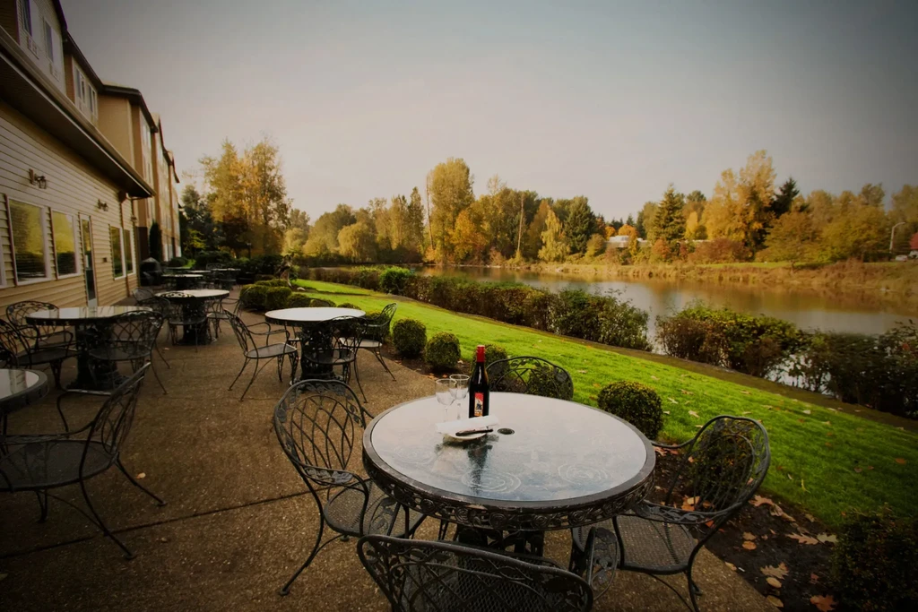 Patio with wine bottle on table overlooking a lake in autumn.
