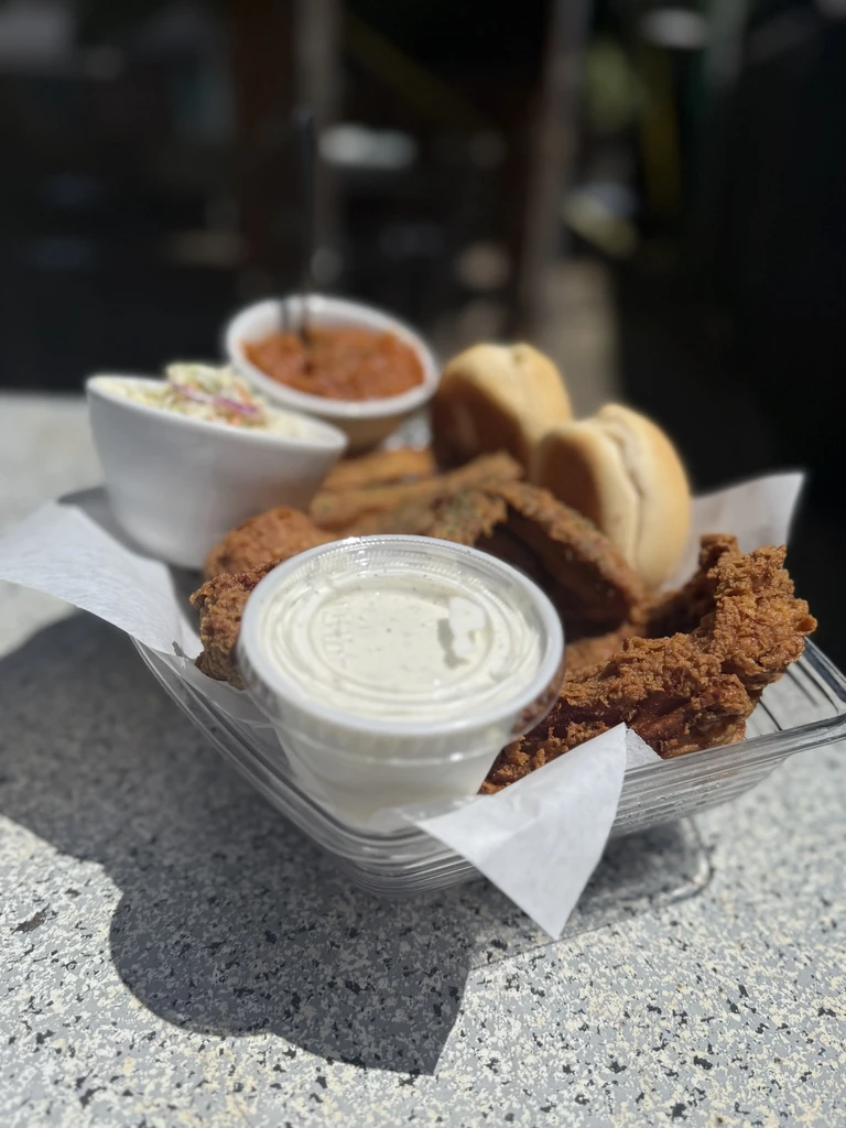 Casual fried chicken basket meal with sides on an outdoor table.