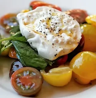 Creamy burrata, fresh basil, and colorful heirloom tomatoes on a plate.