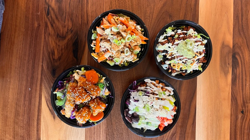 Four colorful, distinct meal bowls on a wooden table.