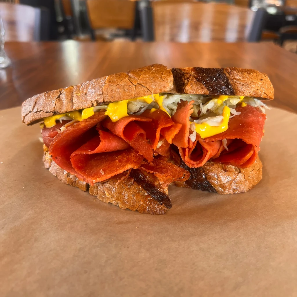 Toasted pastrami sandwich, piled high with sauerkraut and yellow mustard.