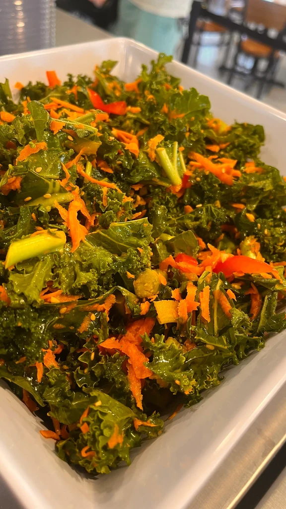 Green kale salad with carrots, red bell pepper, and sesame seeds.