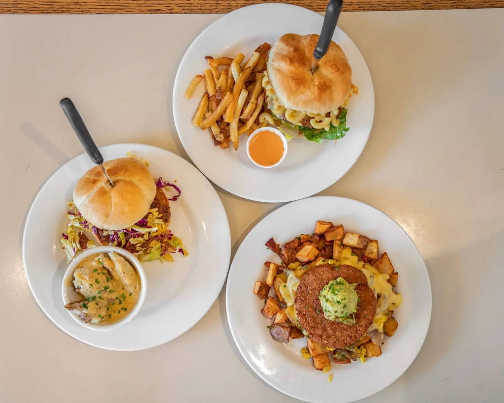 Overhead of three distinct plant-based burger and patty meals with sides.