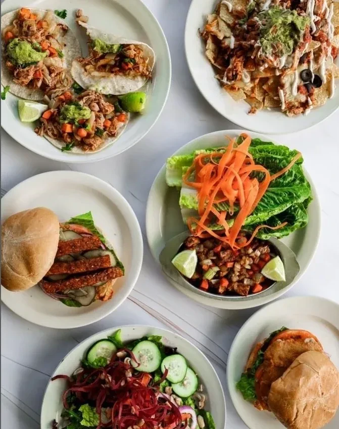 Flat lay of six diverse meals: tacos, nachos, salads, and sandwiches.