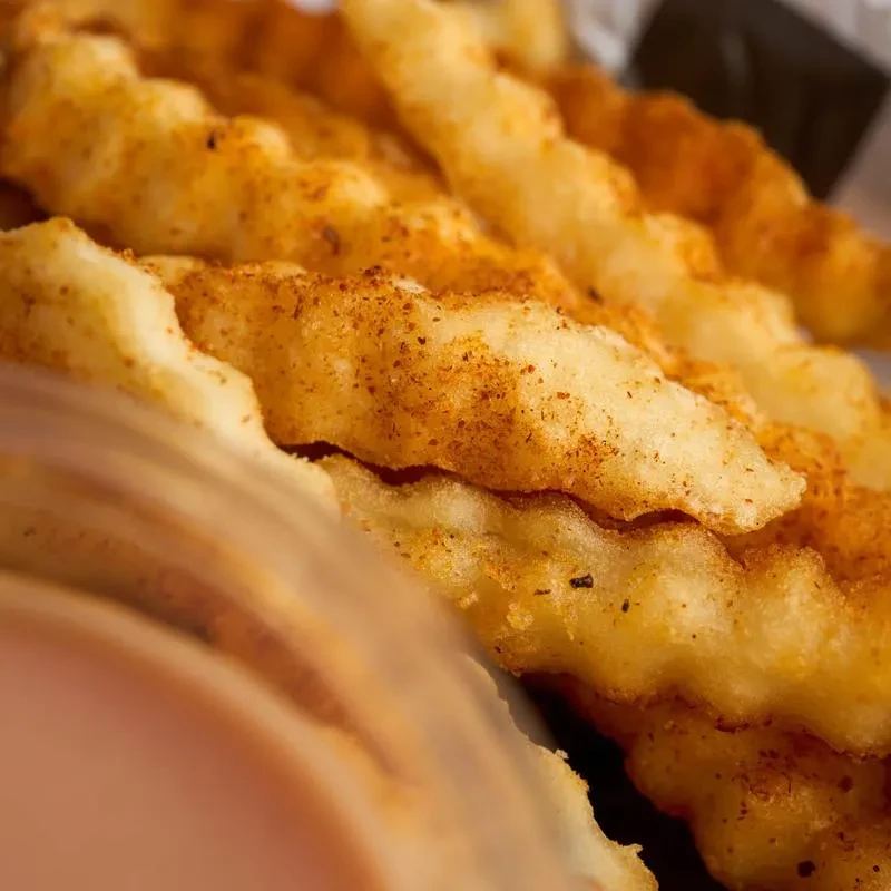Golden-brown crinkle-cut fries heavily seasoned with a reddish spice.