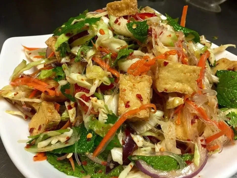 Colorful glass noodle salad with fried tofu, vegetables, and herbs.