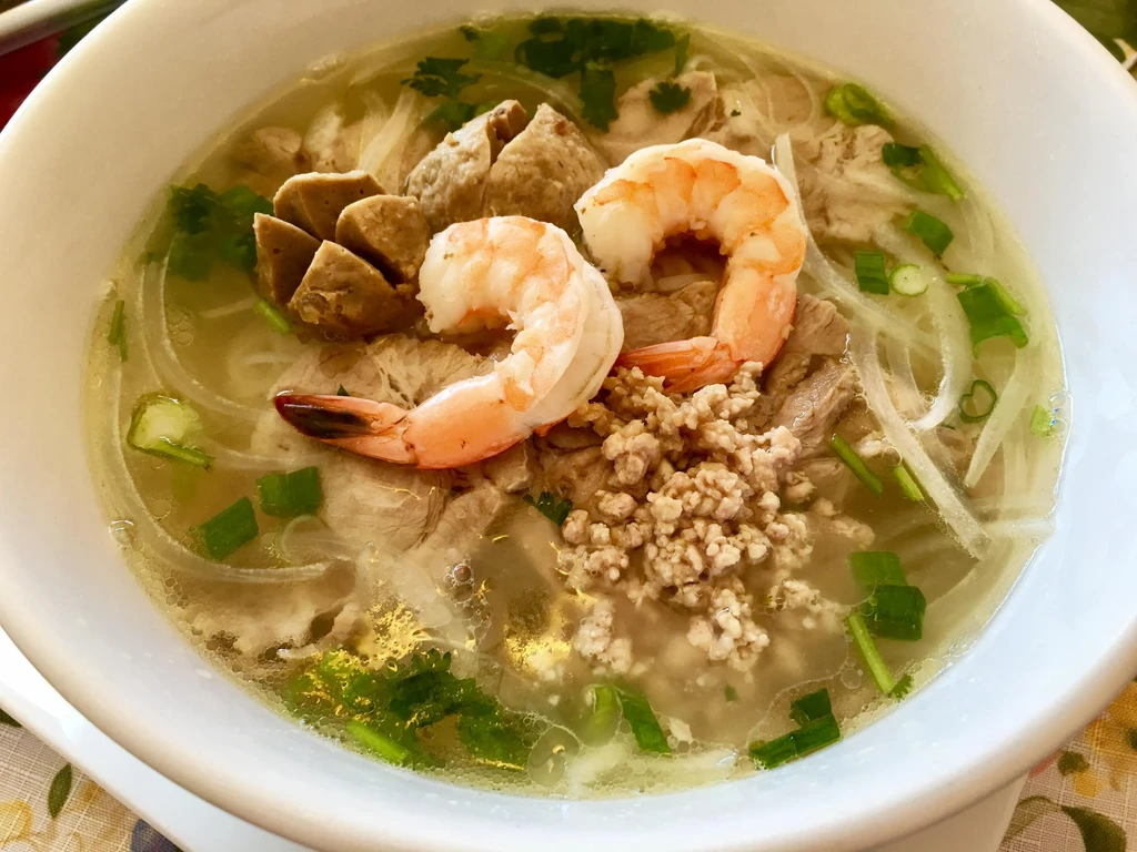 Steaming Vietnamese noodle soup with shrimp, meatballs, and herbs.