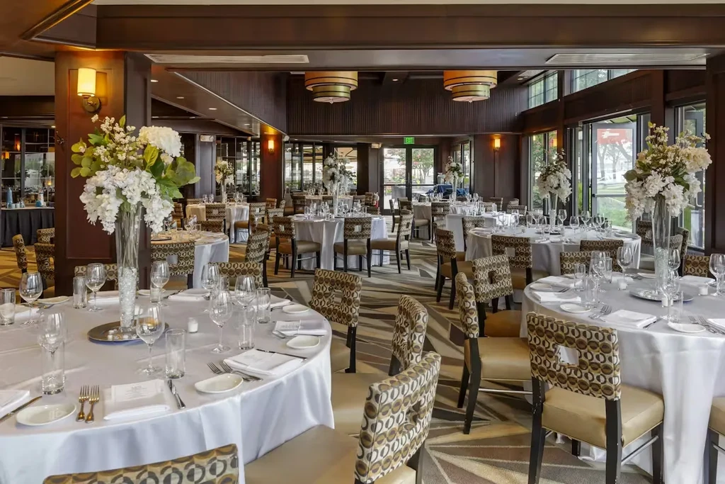 Formal event hall interior with set tables, white flowers, and dark wood.