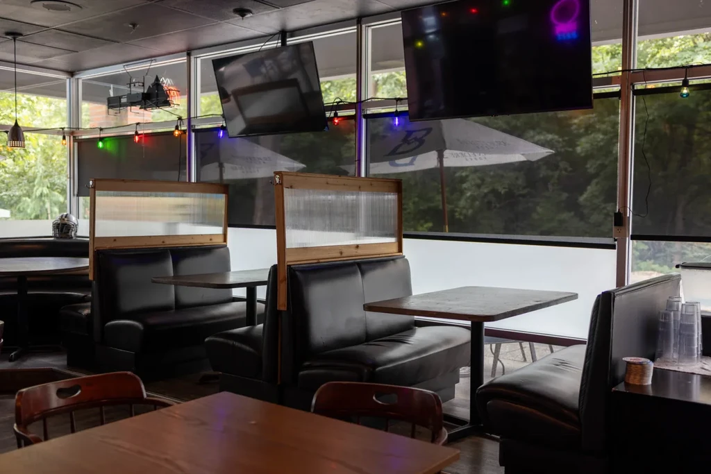 Empty casual restaurant with dark booths, ridged dividers, and large windows.