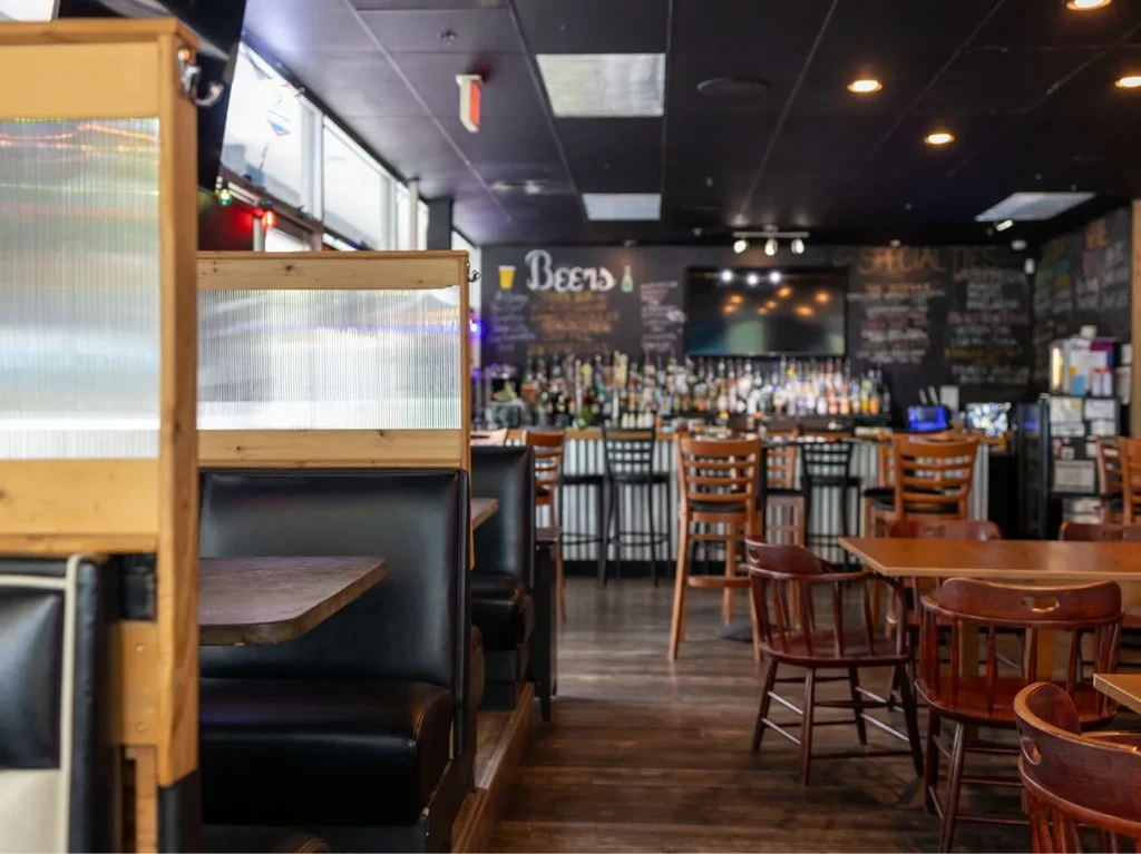 Casual restaurant interior with dark wood furniture and a well-stocked bar.