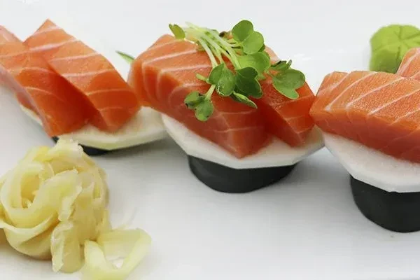 Three salmon sashimi appetizers with daikon, pickled ginger, and wasabi.