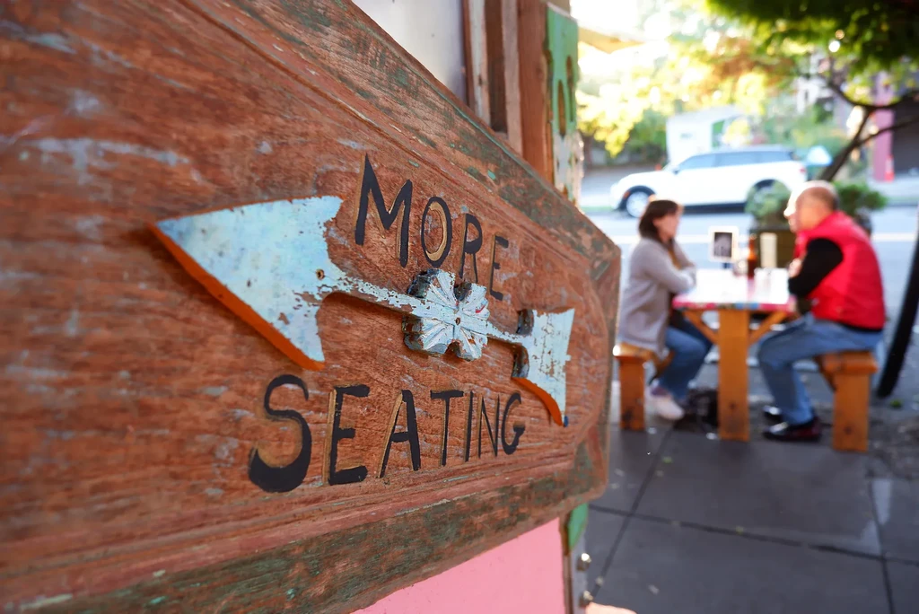 Weathered wooden 'MORE SEATING' sign with a left-pointing arrow.