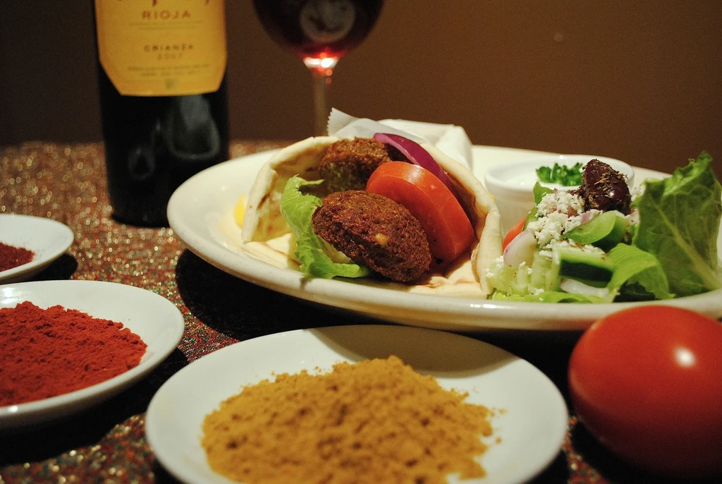 Mediterranean falafel wrap, side salad, red wine, and spices.