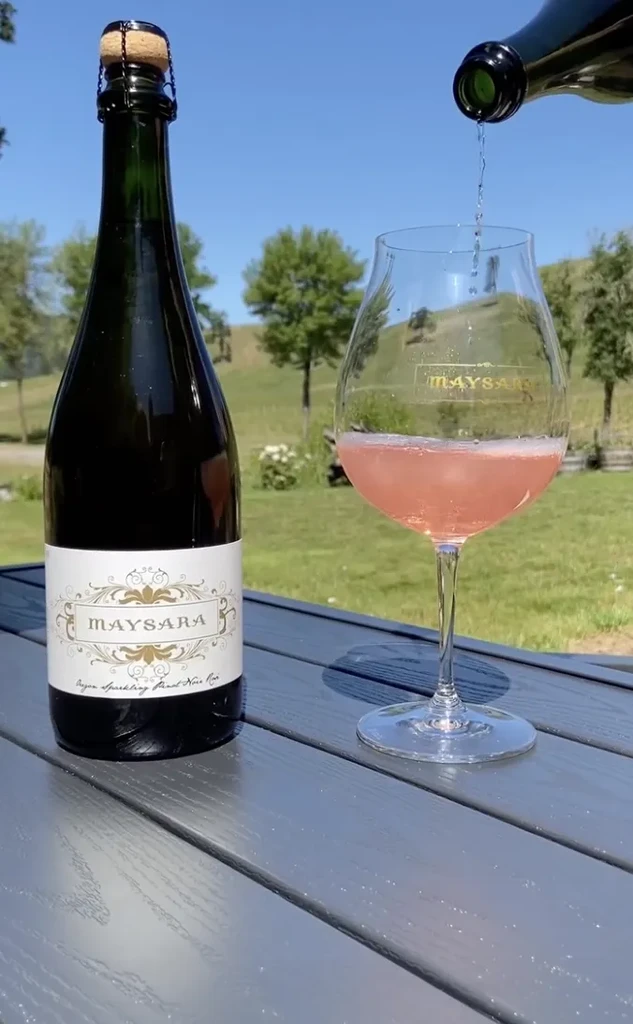 Maysara sparkling rosé bottle, glass on outdoor table, wine pouring.