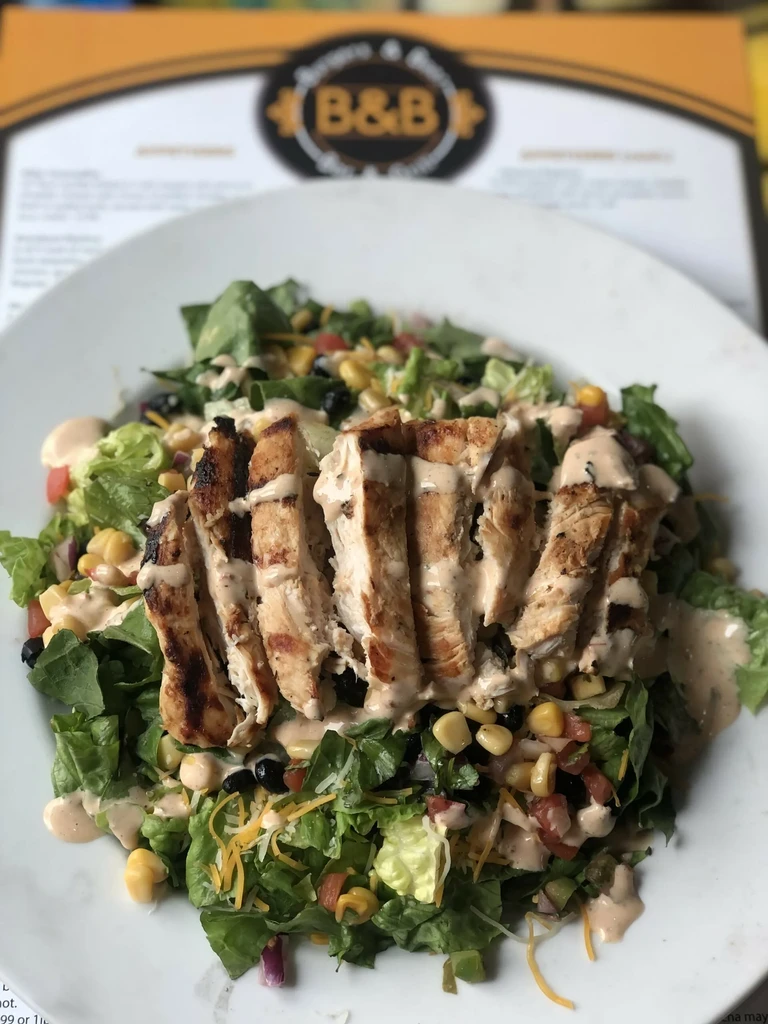 Grilled chicken salad with corn, beans, and cheese in a restaurant.