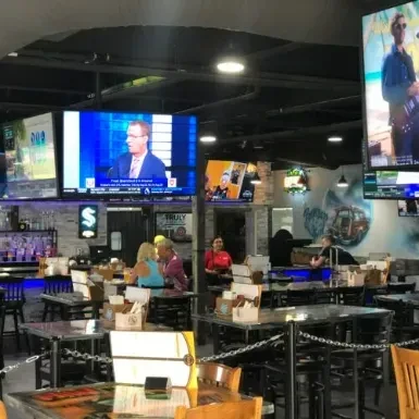 A sports bar interior with multiple TVs showing programs and a bar.