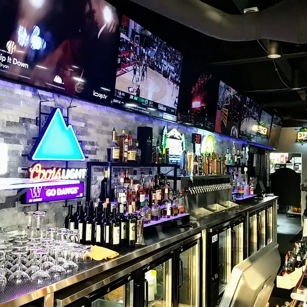 Well-stocked sports bar with neon signs, beer taps, and TVs.