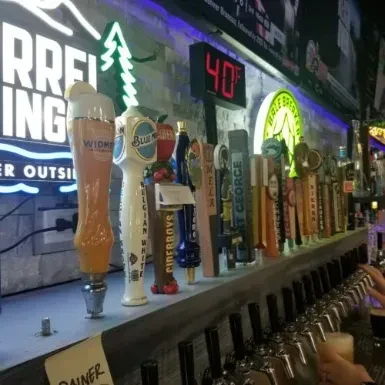 Diverse branded beer taps, neon signs, and hands pouring frothy beer.