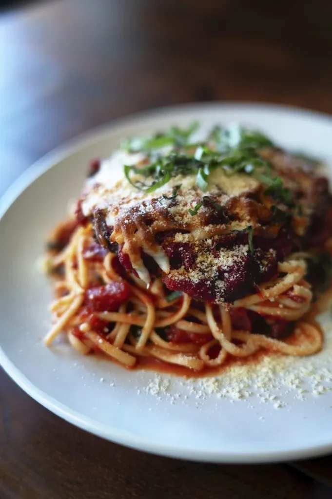 Linguine pasta with tomato sauce, breaded cutlet, melted cheese, and basil.