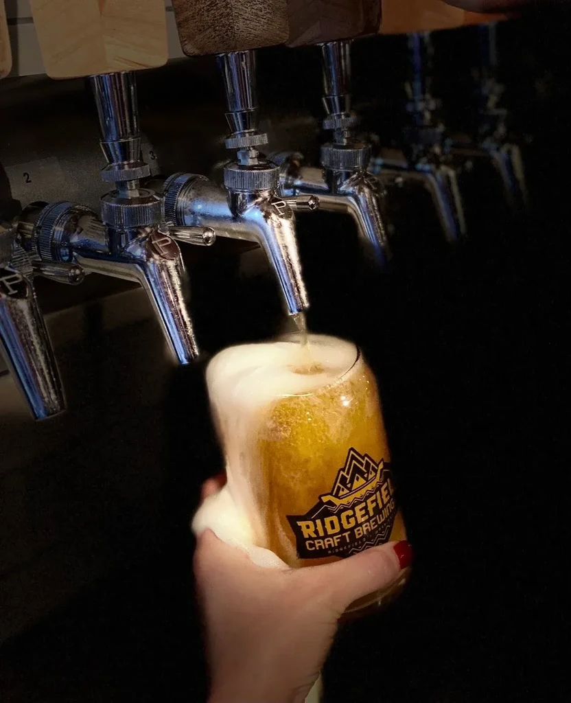 Foamy Ridgefield Craft Brewing beer pours from a tap.