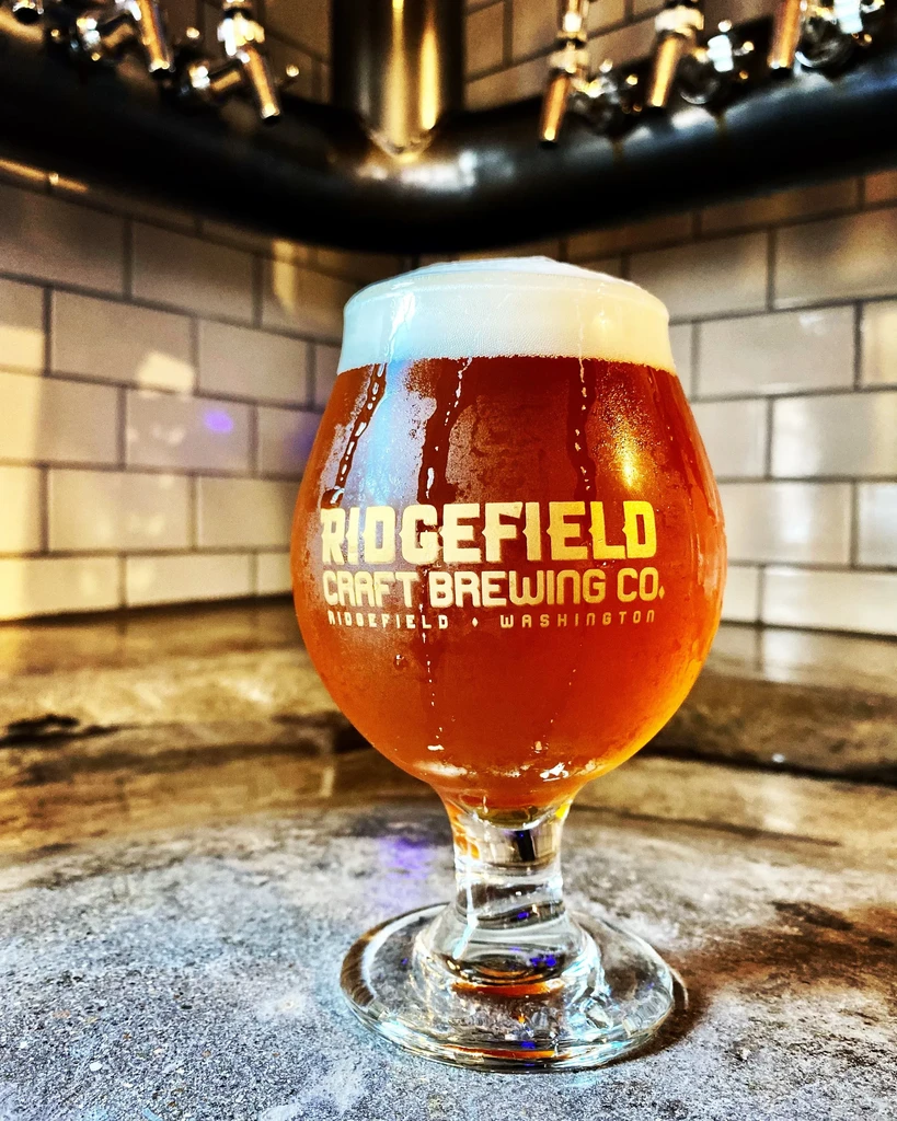 Branded glass of cold amber craft beer with condensation.