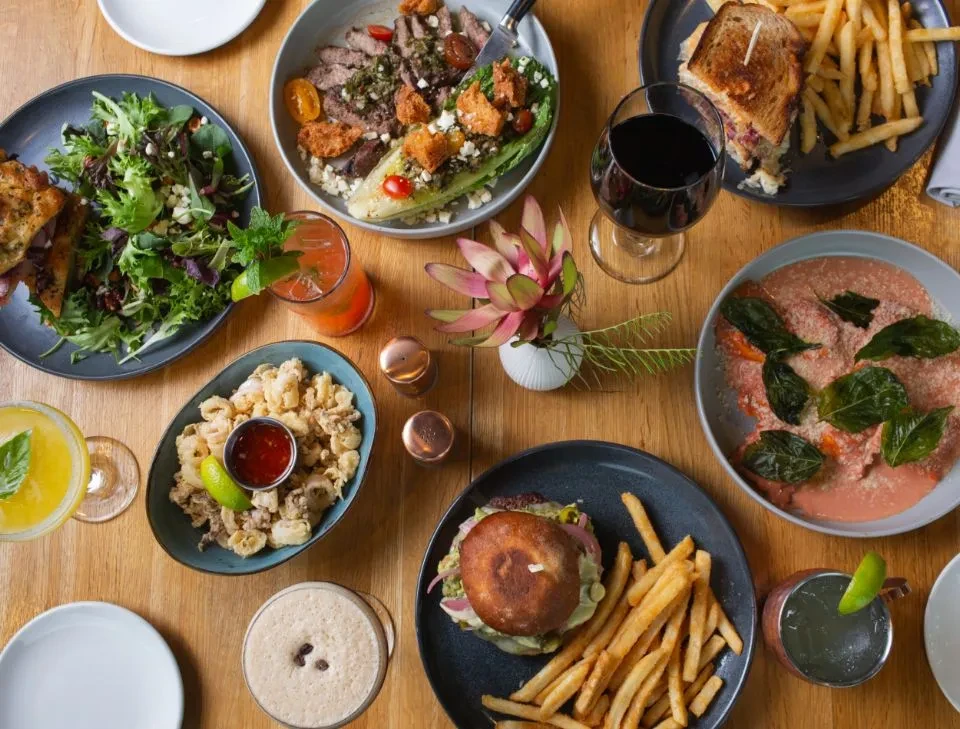 Flat-lay of a dining table laden with diverse dishes and cocktails.