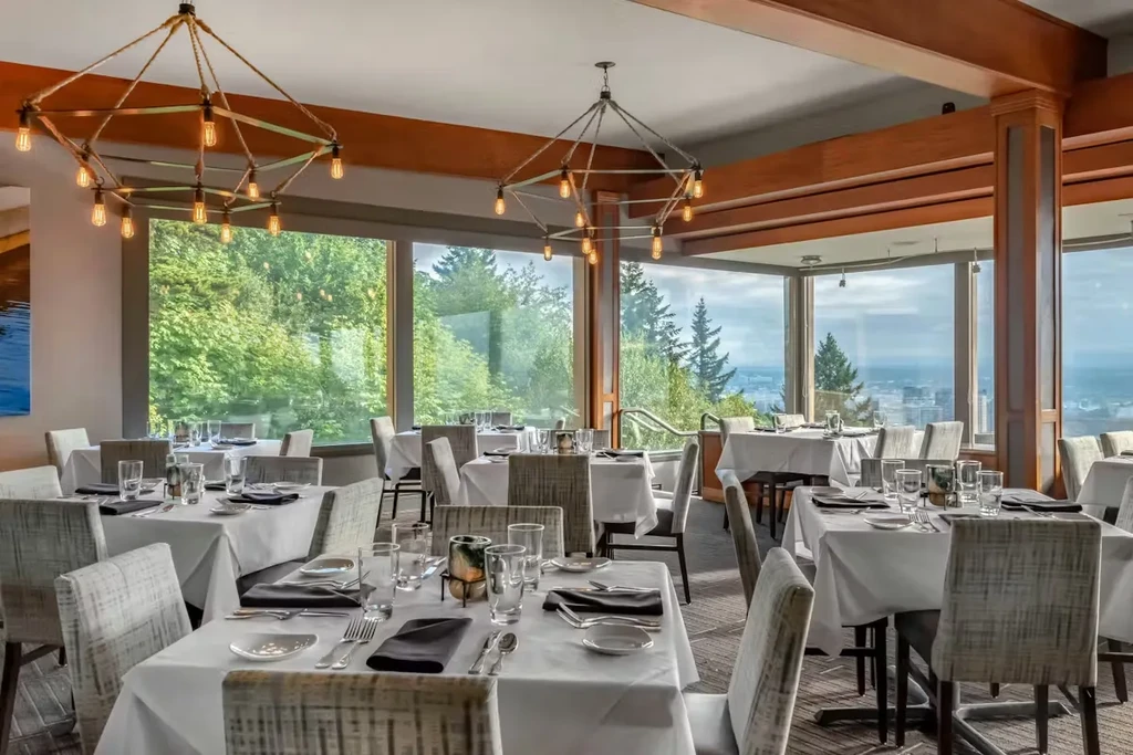 Elegant, spacious restaurant with set tables and a panoramic view.