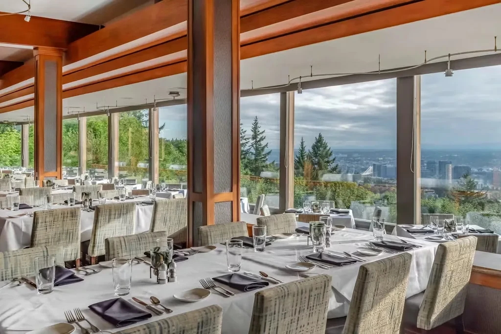Elegant empty restaurant with set tables and a panoramic city view.