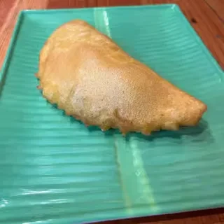 Golden-brown crescent-shaped pastry on a rectangular teal ribbed plate.