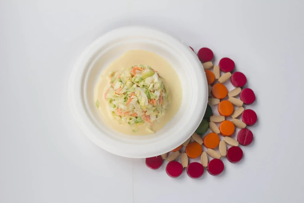 Overhead shot of coleslaw in a white bowl on a colorful woven mat.