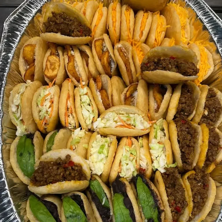 Silver catering tray with mini stuffed savory pockets: meat, plantain, slaw.